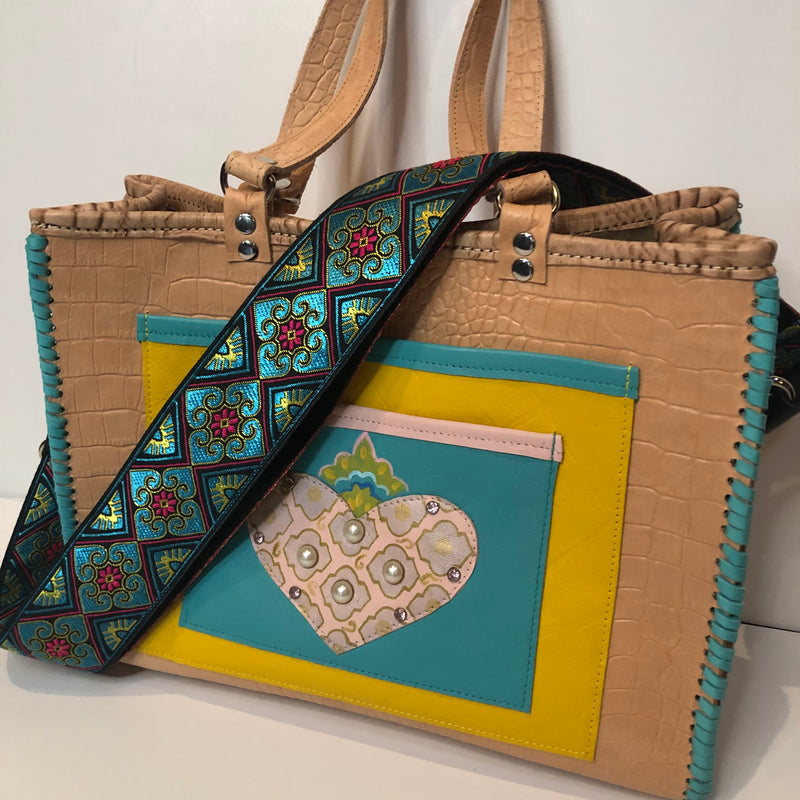 The Valencia Tote with flaming heart applique shown with free bag strap, turquoise color with fuchsia & yellow motif. 