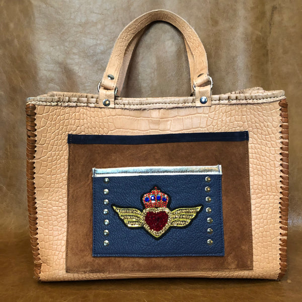 Natural tone croc print leather tote with large pockets & winged heart applique. 