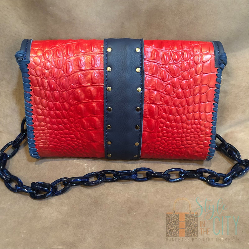Back view of red croc print leather bag with navy & gold accents.