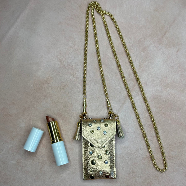 Flat lay of gold leather pouch necklace for lipstick or lip balm, embellished leather on long gold chain.