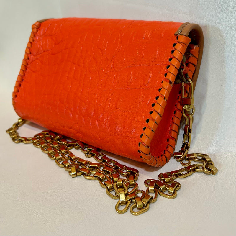 Back side of orange croc leather mini bag with light tan trim.