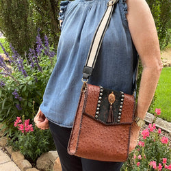 Brown ostrich print leather crossbody with copper concho styled with casual denim outfit