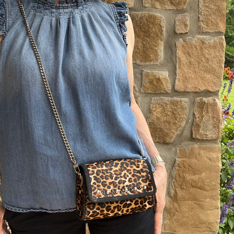 Leopard print leather mini bag with silver stud accents styled with casual denim outfit