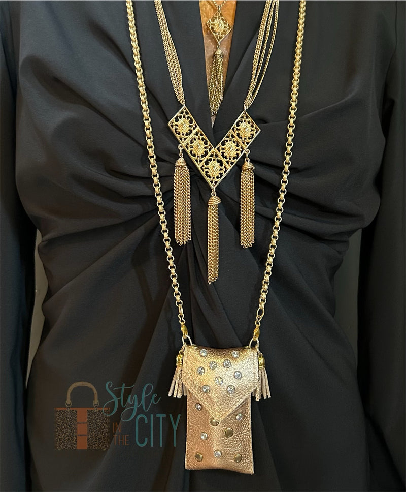 Styled view of gold leather pouch necklace layered with other necklaces.