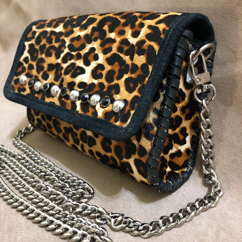 Side view of silver domed studs & onyx  accents of leopard print leather mini bag.