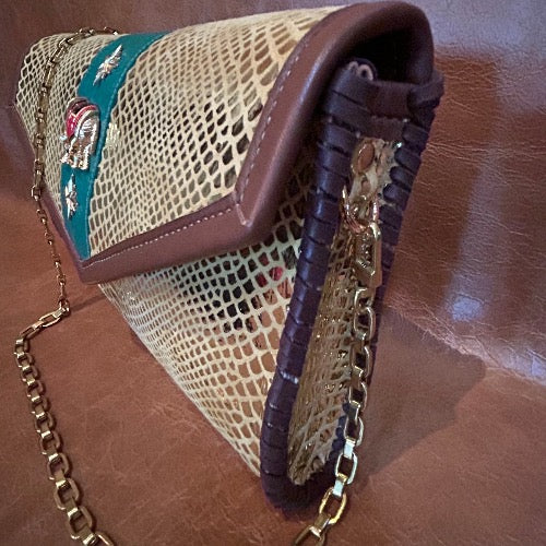Side view of gold snake print leather envelope clutch with vintage elephant