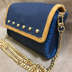 Side view of navy & tan leather mini bag with long gold chain.