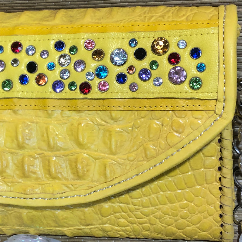 Close up of multicolored crystals on front of yellow croc print leather clutch 