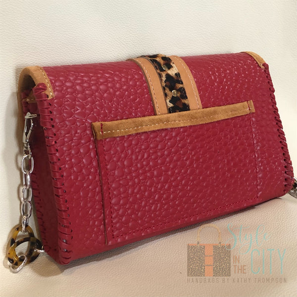Back view of red leather handbag with leopard trim and phone pocket on back.