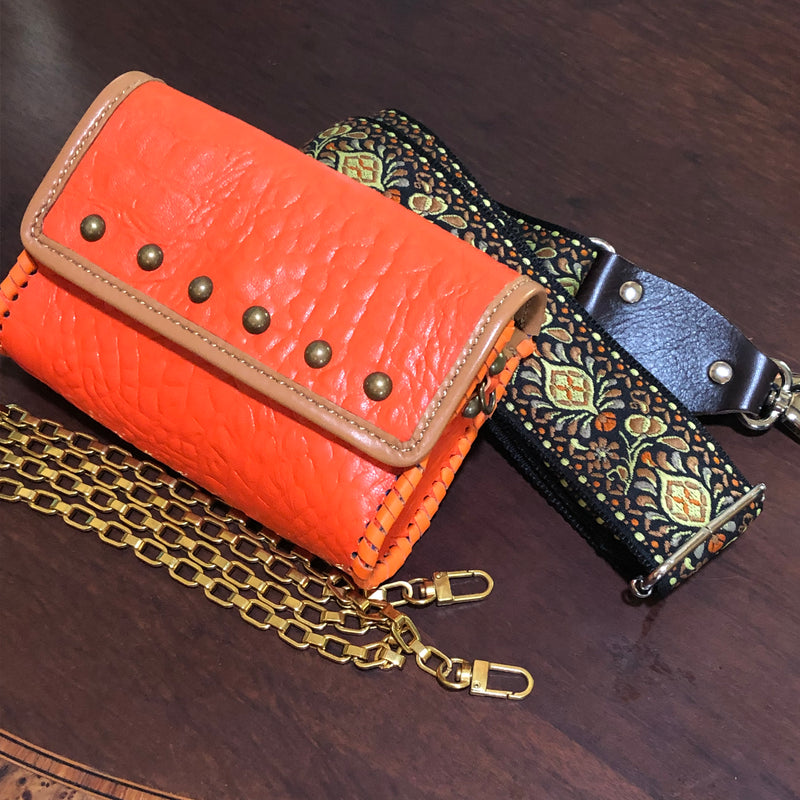 Orange croc leather mini bag with tan trim, domed studs accents, and 2 different straps. 