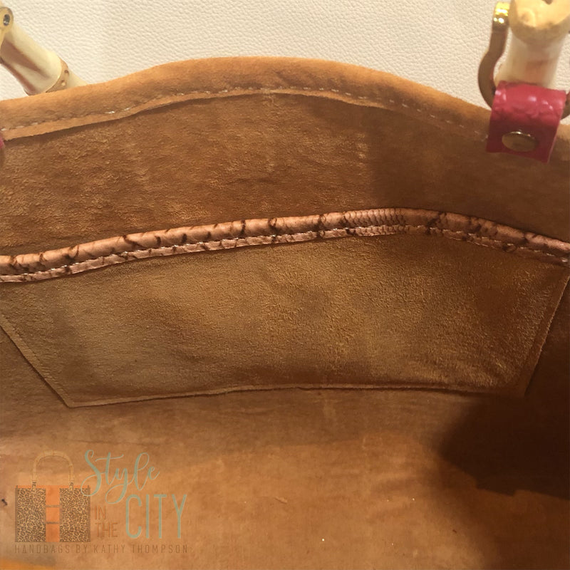 Interior view of tan suede lining and pocket in red and tan leather tote bag with bamboo handles