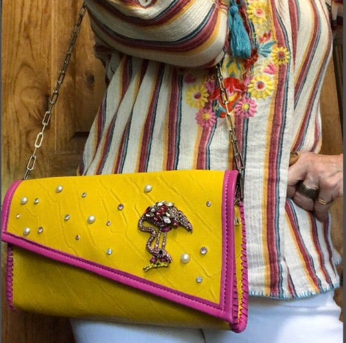 Styled view of yellow croc print leather bejeweled clutch bag with colorful embroidered outfit.