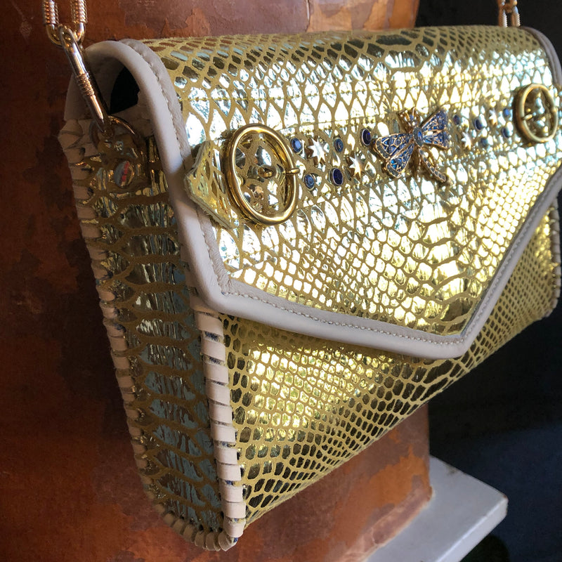 Side view of gold snake print leather clutch with blue crystals