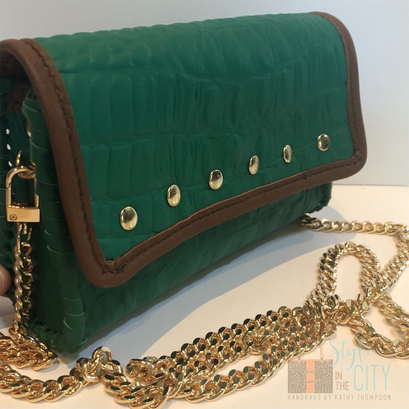 Close up of gold studded accents and brown trim on Emerald green croc leather mini bag. 