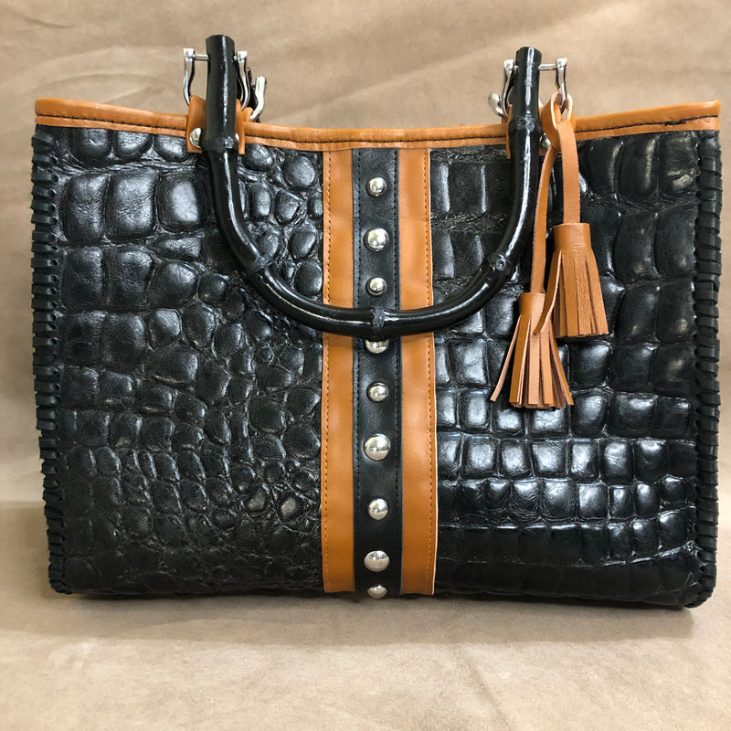 Front view of black croc print leather tote with chestnut brown trim, silver nailheads, & bamboo handles. 