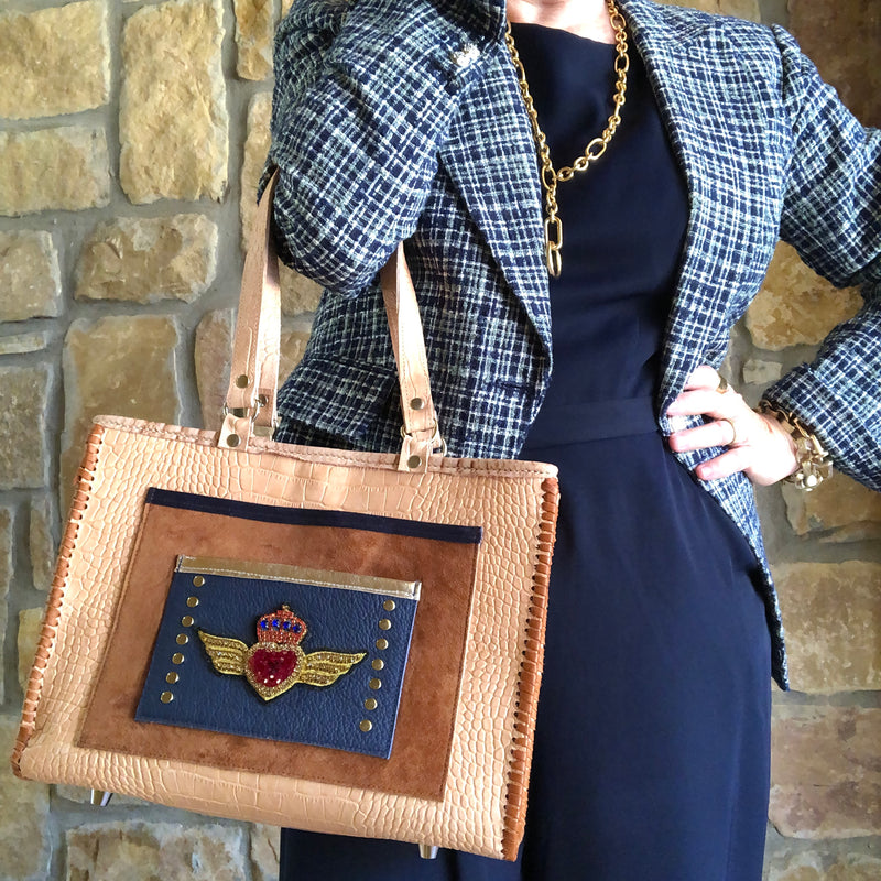 Styled view with office look carrying the Tan croc print leather tote with winged heart applique. 