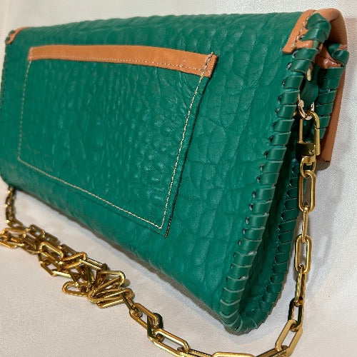 Back view of large pocket on embellished green croc print leather bag with tan trim.