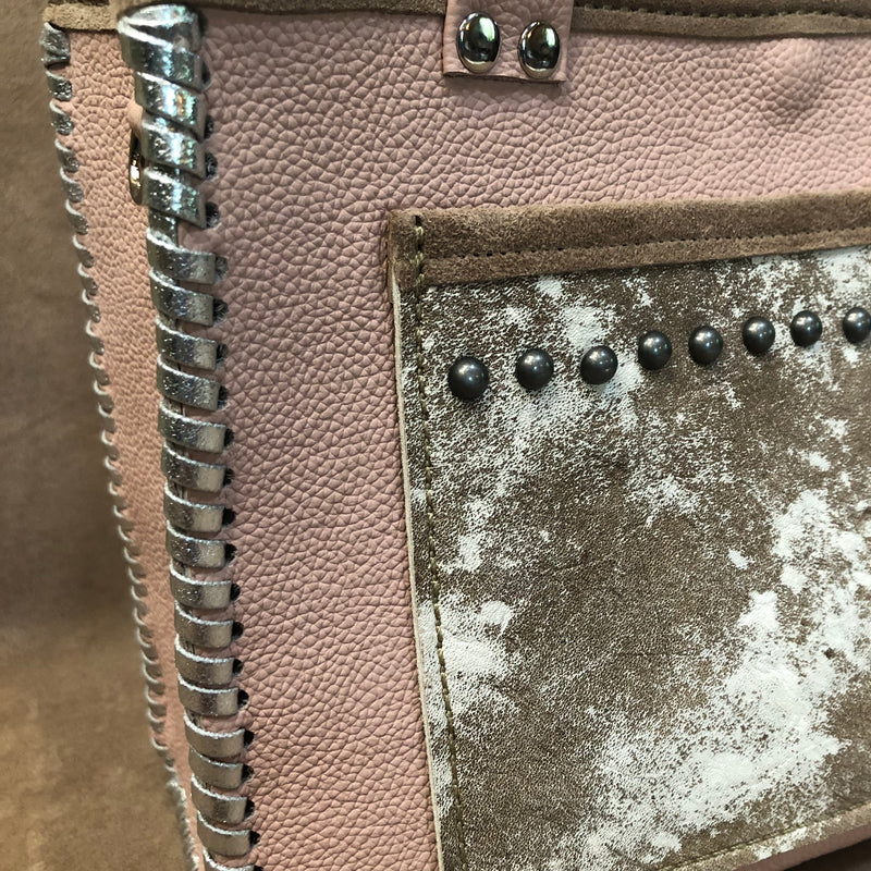 Close up view of silver nailheads and laced edges of blush pink leather petite tote