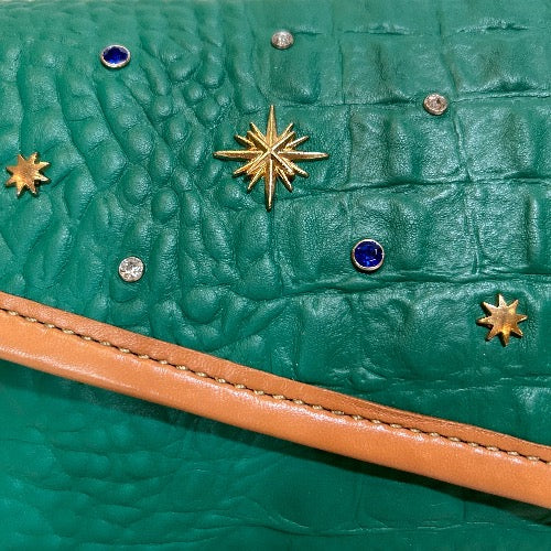 Close up of embellished details on front of green croc print leather bag with tan trim
