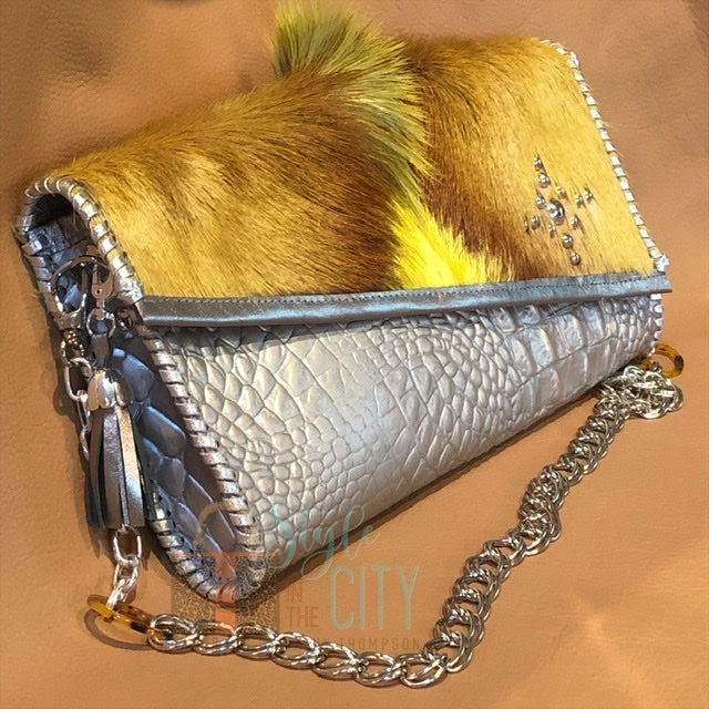 Side view of metallic silver leather clutch with springbok & nailhead accents with chain handle.
