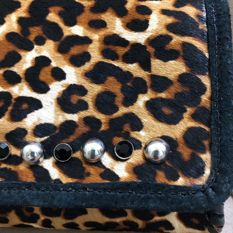 Close up of embellished flap of leopard print leather mini bag.