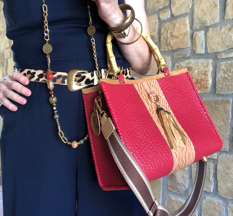 Red and tan leather tote bag with bamboo handles styled with navy jumpsuit outfit.