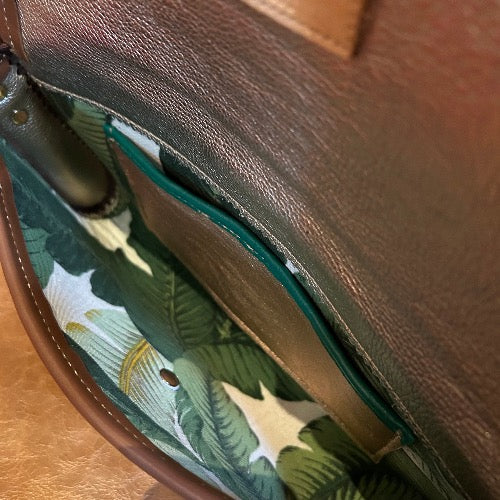 Interior view of leather & tropical print fabric lining inside gold snake print leather envelope clutch.