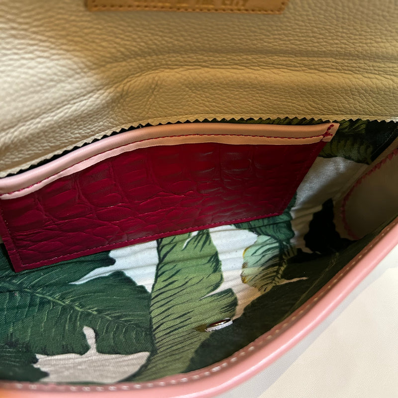 Interior view of tropical print lining of magenta pink leather resort clutch.
