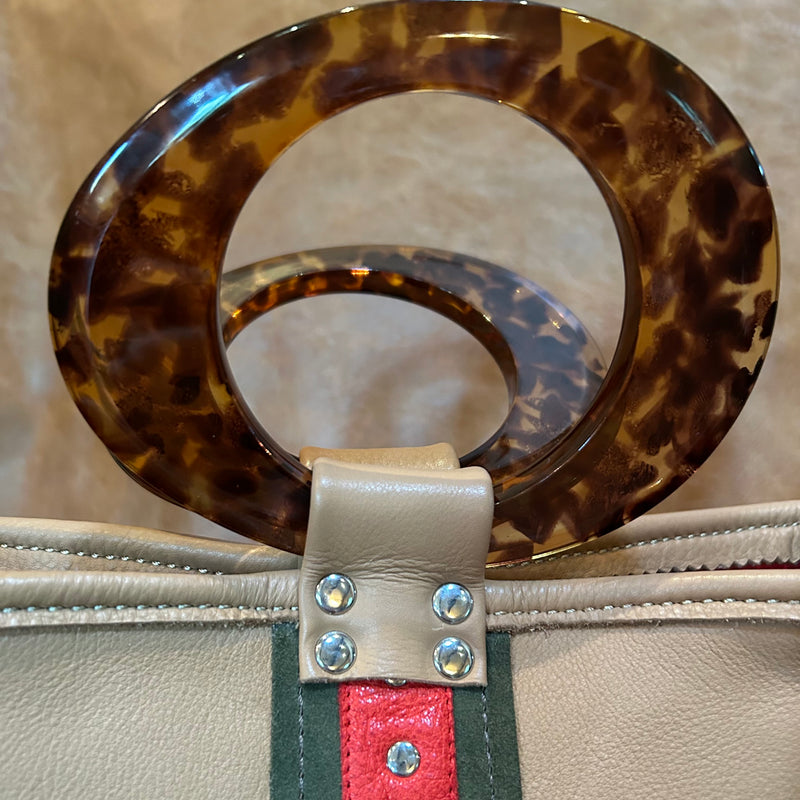 Close up of round tortoise acrylic handles on sporty tan leather tote bag